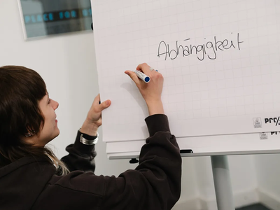 Fred-Kurs | © ©LWLKS/JAlthoff Eine junge Teilnehmerin schreibt das Wort "Abhängigkeit" auf ein Flip Chart | © ©LWLKS/JAlthoff